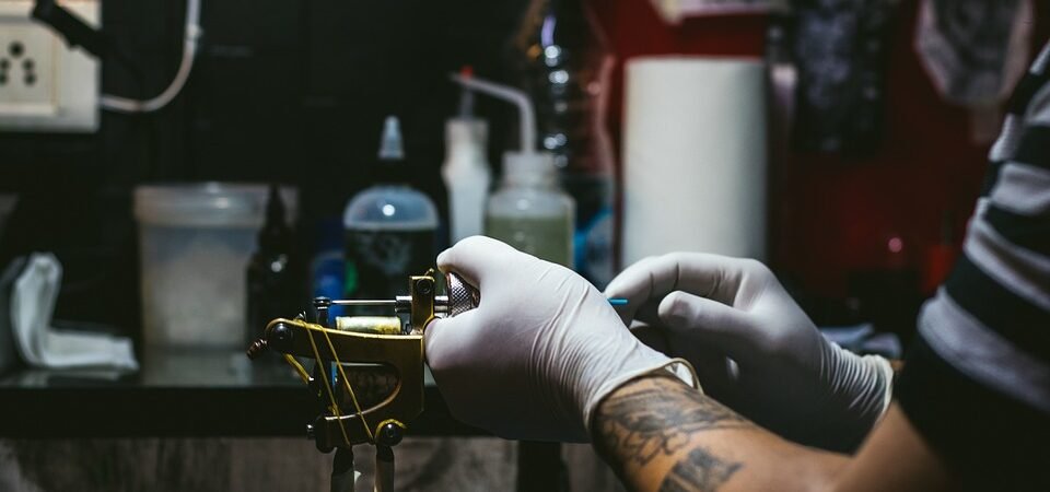 10 cose da sapere prima di fare un tatuaggio: un tatuatore che prepara la macchinetta