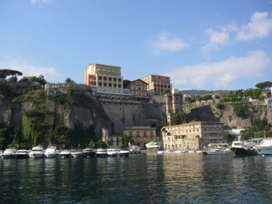 Veduta della spiaggia di Marina Piccola a Sorrento, con stabilimenti balneari e il Vesuvio sullo sfondo.