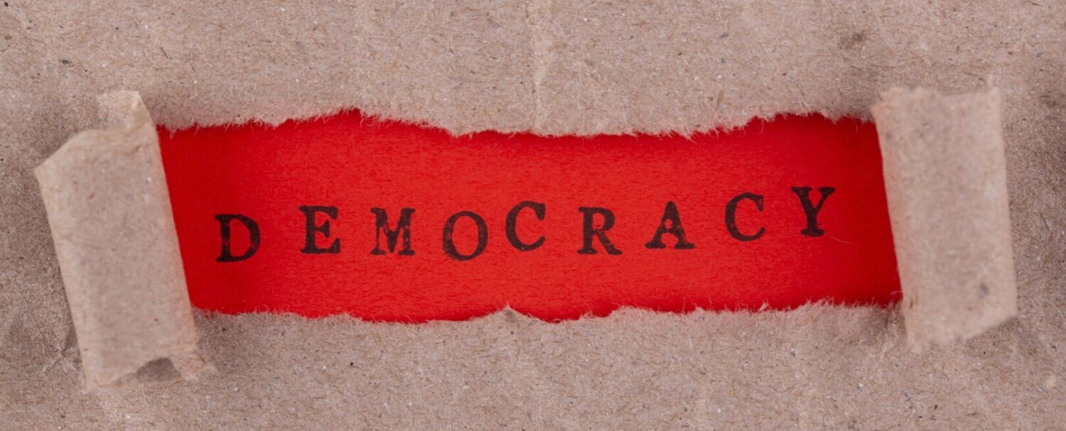 Immagine che rappresenta simbolicamente la crisi di democrazia, con scritta "democracy" al centro.