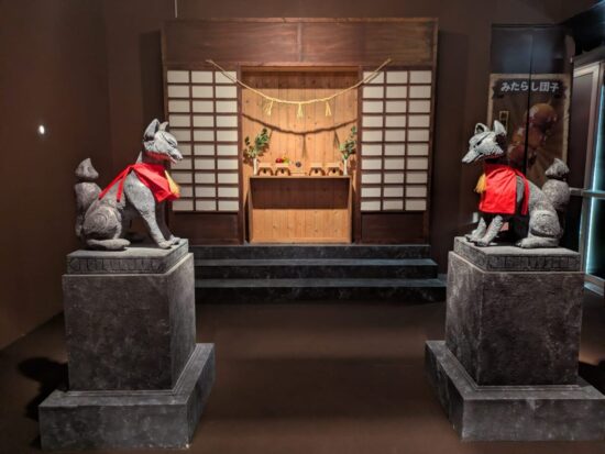 Due kitsune della mostra Itadakimasu che poggiano su dei piedistalli