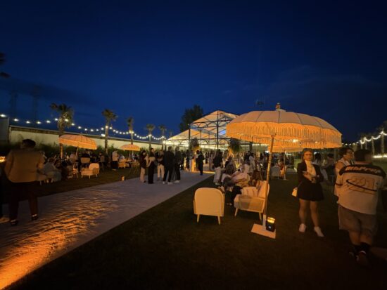 Giardino esterno con sedute illuminate e vetrata di notte presso Lumea Events